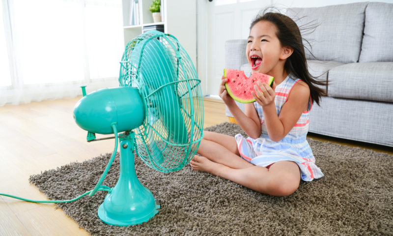 girl eating a watermelon in front of fan at high speed