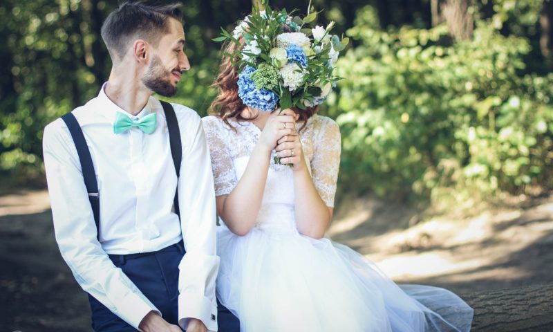 adult couple newlyweds on their wedding day holding bouquet and having fun