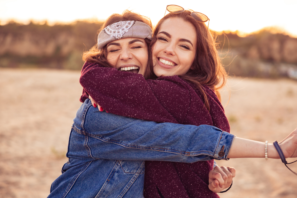 two women friends giving hugs and laughing together