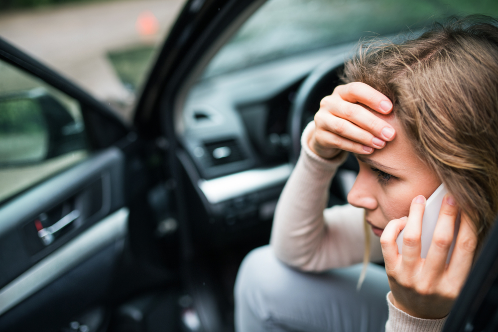 woman sitting in a car making a call looking worried