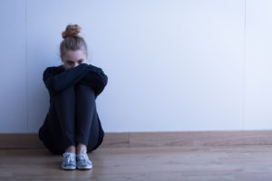 woman sitting on floor looking depressed as a result of mental health