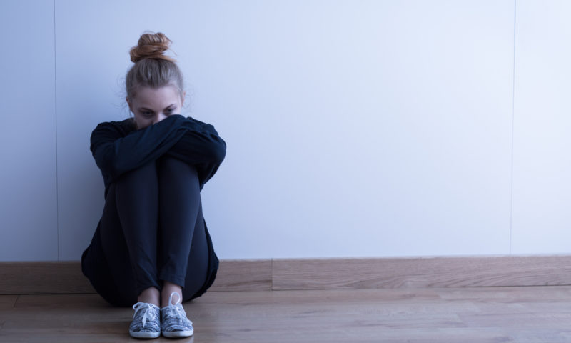 woman sitting on floor looking depressed as a result of mental health