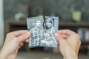 person tearing a photograph of a couple after a breakup or divorce